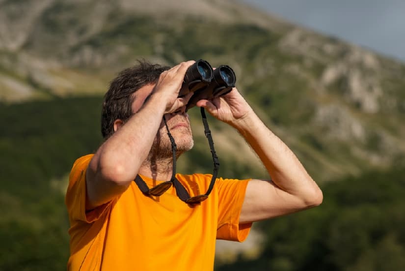 Hombre observando aves con ayuda de unos binóculos